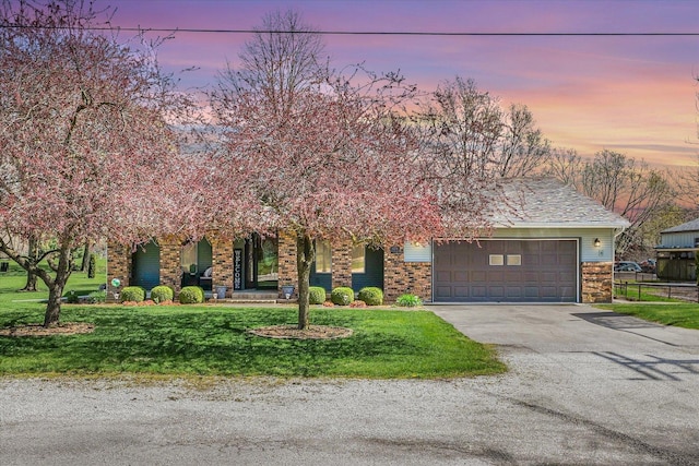 obstructed view of property featuring driveway, a garage, and a front yard