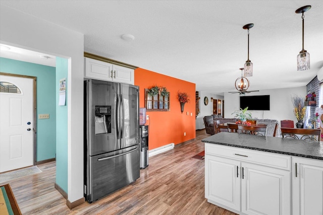 kitchen featuring pendant lighting, light wood finished floors, open floor plan, white cabinets, and stainless steel fridge