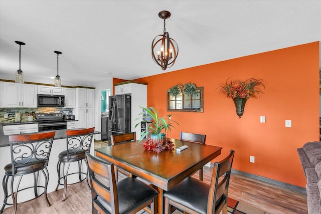 dining area featuring light wood-style floors and a notable chandelier