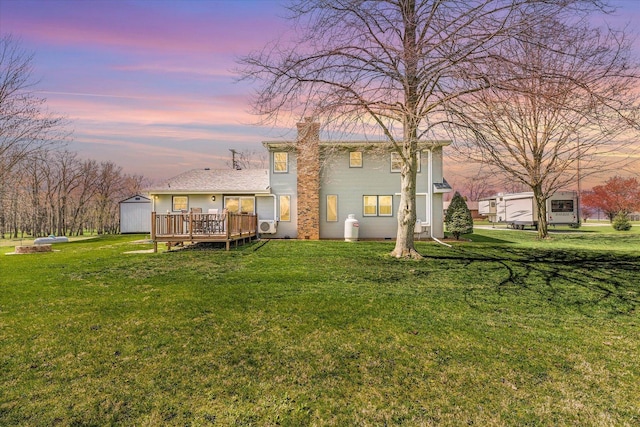 back of house featuring a shed, a lawn, an outdoor structure, and a wooden deck