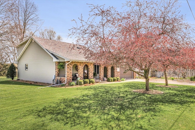 view of front of home featuring brick siding, roof with shingles, an attached garage, driveway, and a front lawn