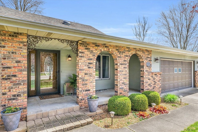 view of exterior entry with covered porch, brick siding, and an attached garage