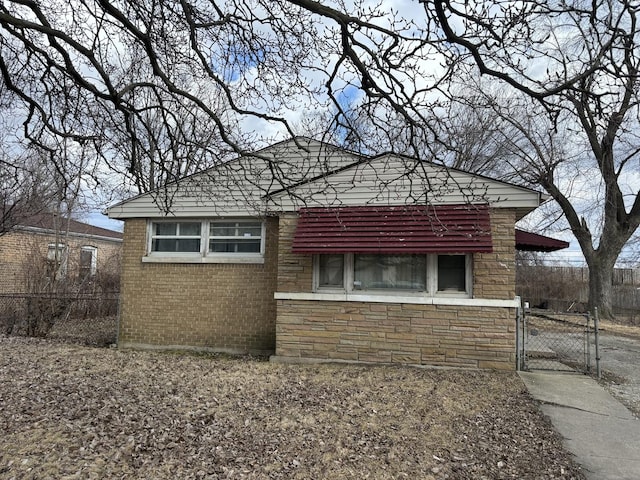 view of home's exterior featuring stone siding, a gate, fence, and brick siding