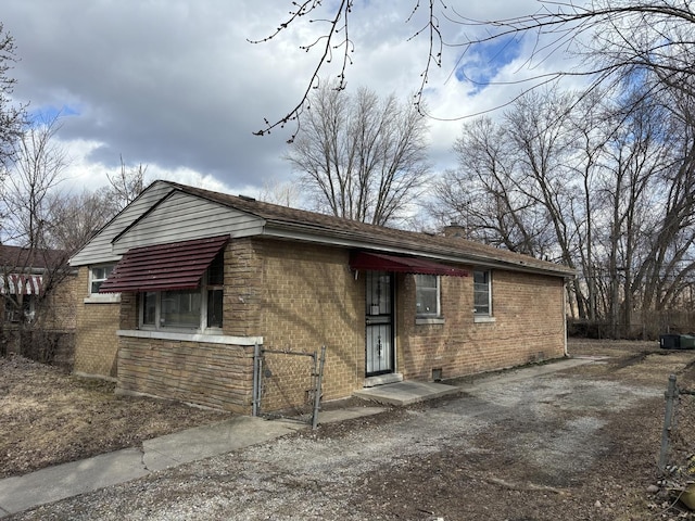 view of front of home featuring stone siding, a chimney, a gate, fence, and brick siding