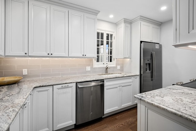 kitchen with dark wood-style flooring, a sink, white cabinets, appliances with stainless steel finishes, and tasteful backsplash