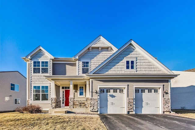 craftsman-style home with driveway and stone siding