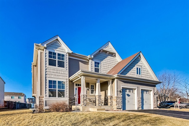 view of front of house featuring aphalt driveway, a porch, a front yard, a garage, and stone siding