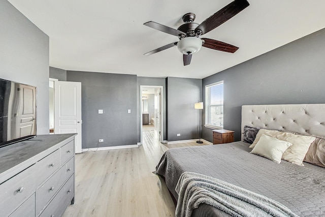 bedroom with baseboards, ensuite bath, a ceiling fan, and light wood-style floors