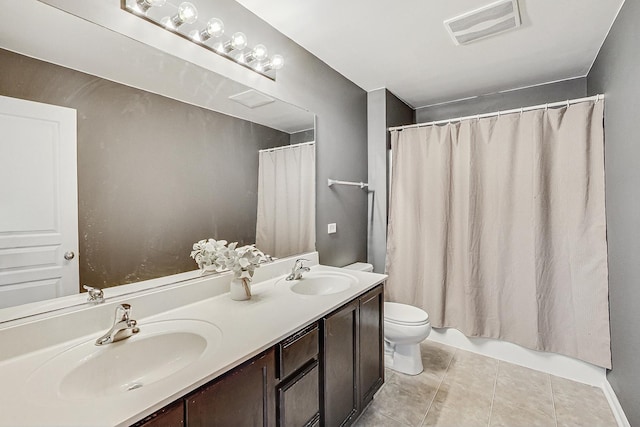 bathroom featuring toilet, double vanity, a sink, and visible vents