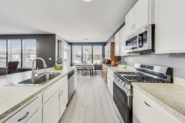 kitchen featuring a sink, white cabinets, light wood-style floors, light countertops, and appliances with stainless steel finishes