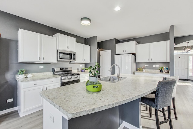 kitchen with appliances with stainless steel finishes, light countertops, white cabinets, and a sink