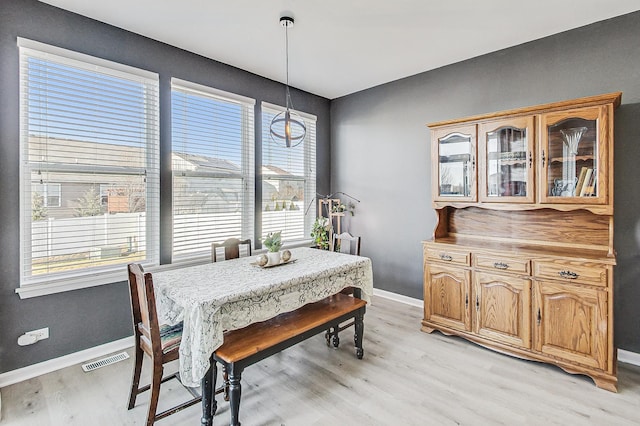 dining area with light wood-type flooring, visible vents, and baseboards