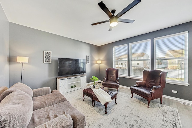 living area featuring baseboards, ceiling fan, visible vents, and wood finished floors