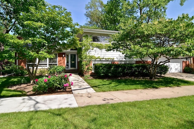 split level home featuring a garage, driveway, brick siding, and a front lawn