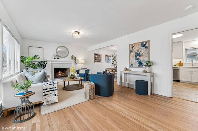 living area featuring a lit fireplace and light wood finished floors