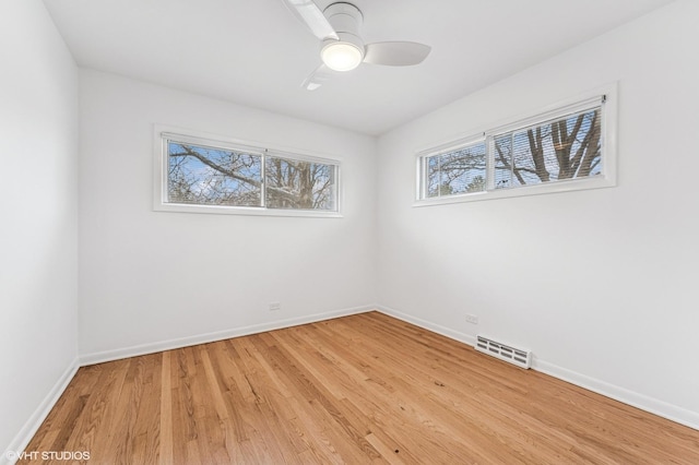 spare room featuring a ceiling fan, visible vents, light wood-style flooring, and baseboards