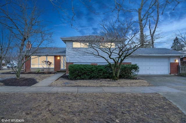 tri-level home featuring aphalt driveway, brick siding, fence, and an attached garage