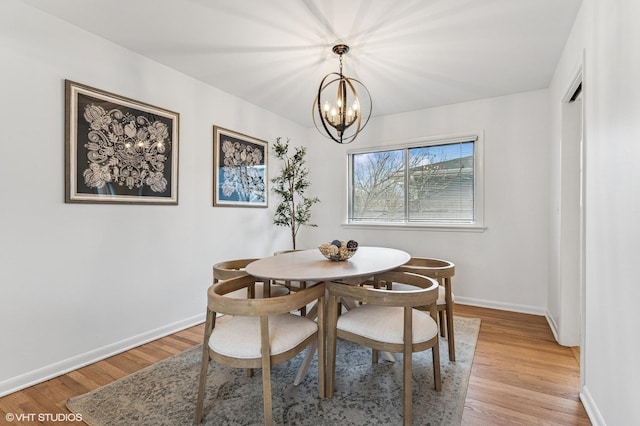 dining room featuring light wood-style flooring, baseboards, and an inviting chandelier