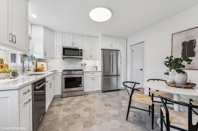 kitchen featuring backsplash, white cabinetry, stainless steel appliances, and a sink