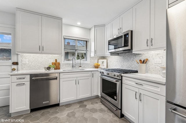 kitchen with white cabinets, decorative backsplash, appliances with stainless steel finishes, a sink, and recessed lighting