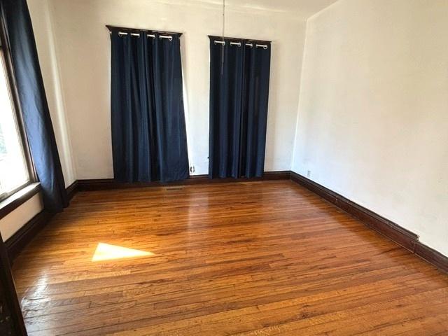 spare room with baseboards and wood finished floors