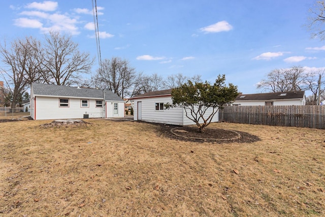 back of house with a yard, fence, and an outbuilding