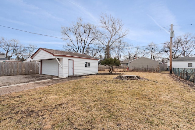 view of yard with a fenced backyard, a detached garage, and an outdoor structure