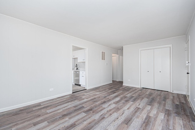 unfurnished bedroom featuring light wood-type flooring, baseboards, visible vents, and a closet