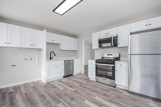 kitchen featuring stainless steel appliances, white cabinets, light countertops, and a sink