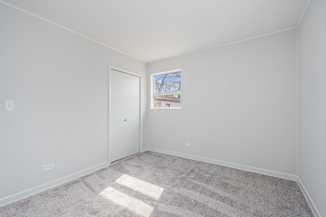 carpeted empty room featuring ornamental molding and baseboards