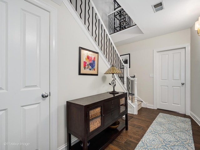 foyer entrance featuring dark wood-style floors, stairway, visible vents, and baseboards