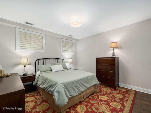 bedroom with wood finished floors, visible vents, and baseboards