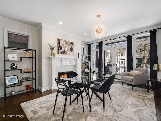 dining area with wood finished floors, a lit fireplace, crown molding, french doors, and a chandelier