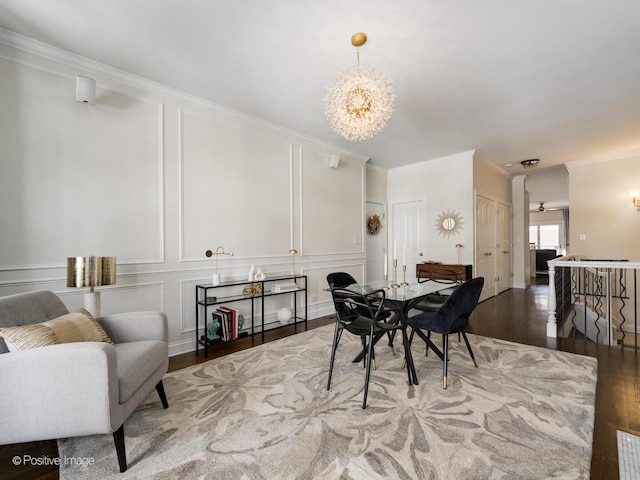 dining room featuring a chandelier, a decorative wall, wood finished floors, and ornamental molding