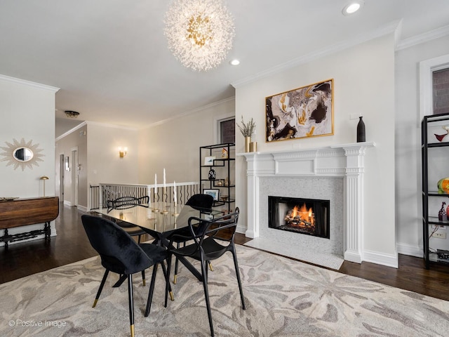 dining area with a fireplace with flush hearth, crown molding, baseboards, and wood finished floors