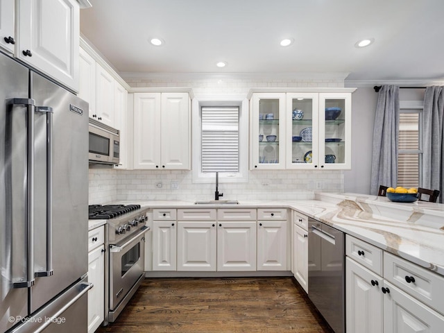 kitchen featuring high end appliances, light stone counters, dark wood-style flooring, white cabinetry, and a sink