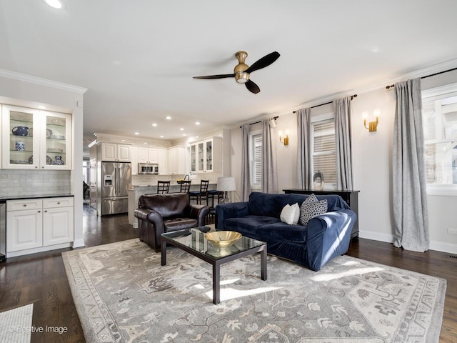 living area with recessed lighting, dark wood-type flooring, a ceiling fan, baseboards, and ornamental molding