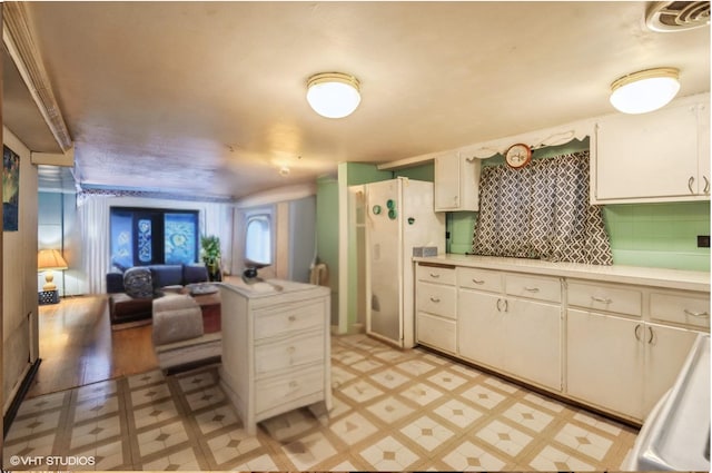 kitchen with white cabinets, open floor plan, light countertops, freestanding refrigerator, and light floors