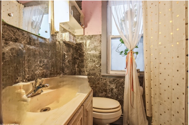 bathroom with toilet, backsplash, vanity, and tile walls