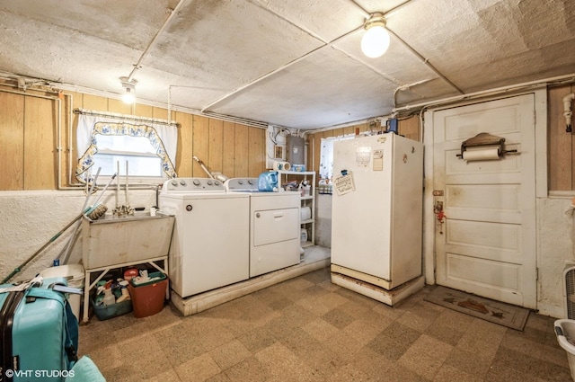 laundry area featuring laundry area, wooden walls, independent washer and dryer, light floors, and a sink