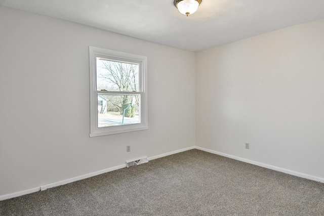 spare room with visible vents, dark carpet, and baseboards