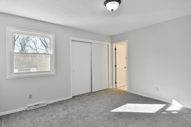 unfurnished bedroom featuring carpet, a closet, visible vents, and baseboards