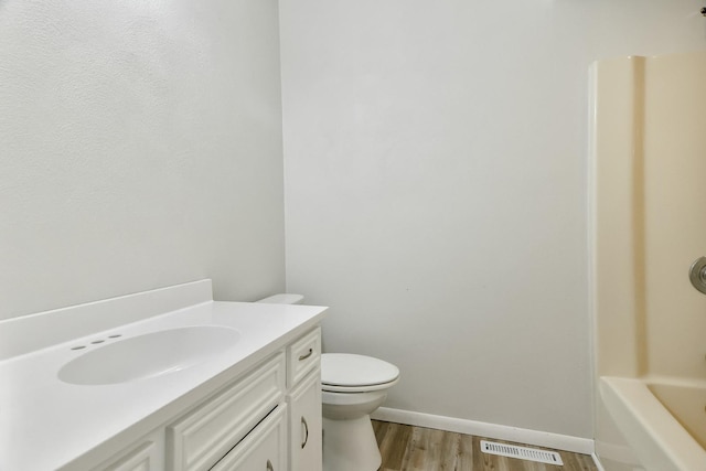 bathroom with visible vents, toilet, vanity, wood finished floors, and baseboards