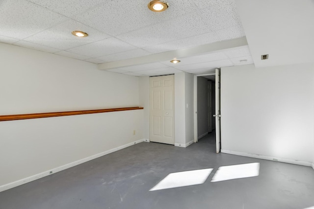 spare room featuring a drop ceiling, concrete floors, visible vents, and baseboards