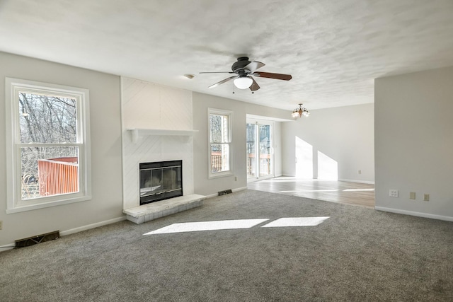 unfurnished living room featuring a large fireplace, plenty of natural light, carpet flooring, and baseboards