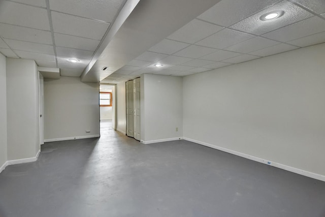 basement with a drop ceiling and baseboards