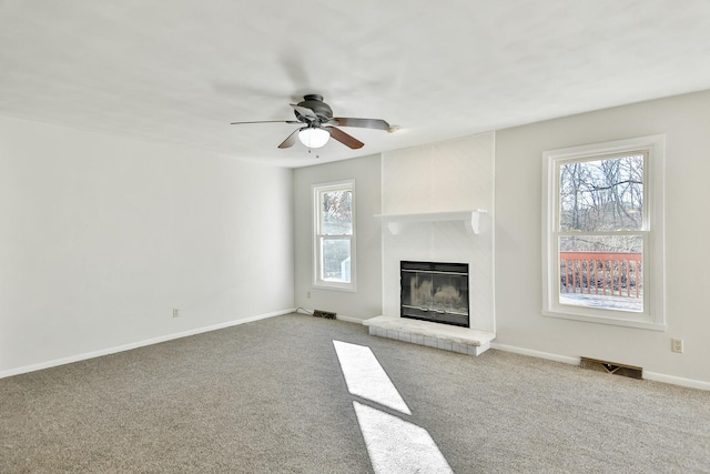 unfurnished living room featuring carpet flooring, a glass covered fireplace, visible vents, and baseboards