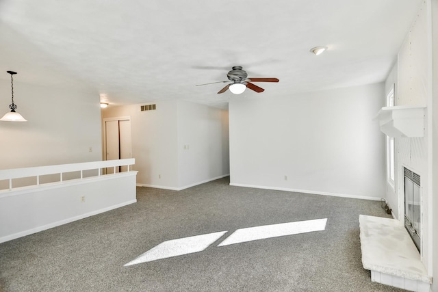 unfurnished living room featuring carpet, visible vents, a large fireplace, ceiling fan, and baseboards