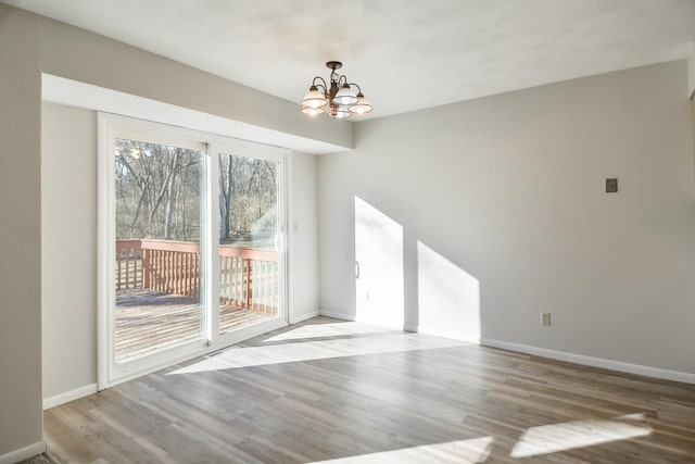 unfurnished dining area featuring a chandelier, wood finished floors, and baseboards