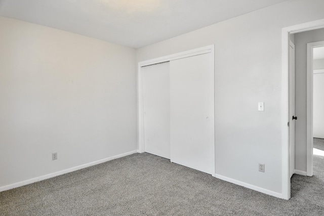 unfurnished bedroom with a closet, carpet, and baseboards